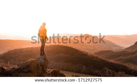 Sweaty mountain hiker with a just has reached a mountain summit. Discovery travel destination concept. Summer landscape surrounded by specific mountains. Strong daybreak sun makes flares in camera 