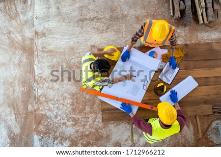 High angle view of engineer and architect discussing building plan at construction site,Group of builders having conversation about building plan.