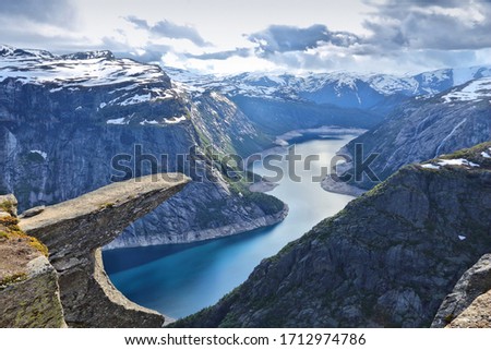 Troll's Tongue rock in Norway. Tourist attraction known as Trolltunga. Rock pulpit over lake. Royalty-Free Stock Photo #1712974786