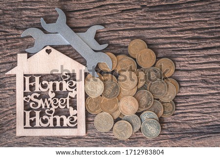 Wooden toy house and repair tools on a wooden floor with a coin-filled copying area. Real estate concept, new home concept, business concept, financial loan, maintenance concept