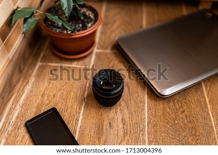 flat lay. laptop, cell phone, lens, flower stand on a wooden background. top view