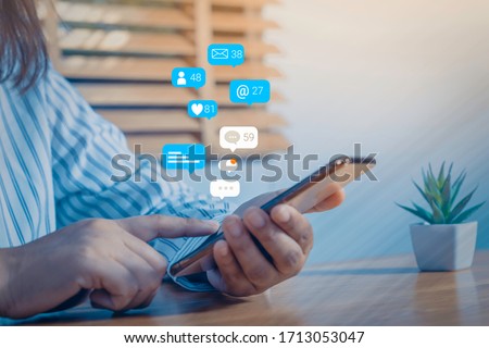 Person using a social media marketing concept on mobile phone with notification icons of like, message, comment and star above smartphone screen. Royalty-Free Stock Photo #1713053047