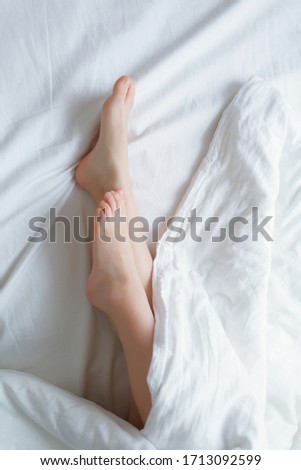 Stock Photo - Female's legs beauty on white bed. Beauty heels of the foot. Top view