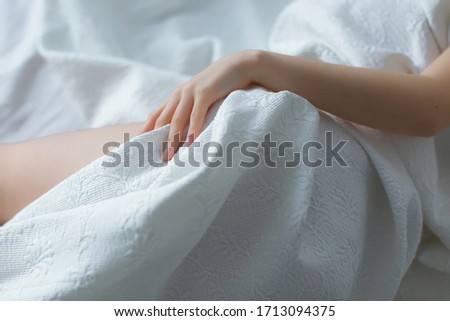 Stock Photo - Female's legs with hand on white bed. Beauty heels of the foot. Top view