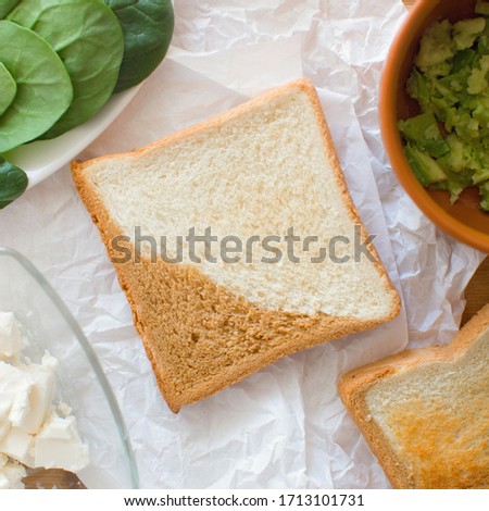 Stock Photo - Tasty sandwiche with toast bread, avocado and cottage cheese close-up on a paper napkin