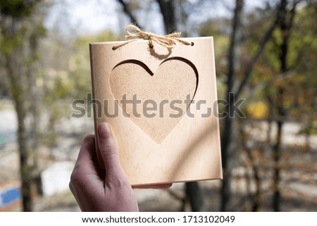 A wooden heart-shaped photo frame on the hand. Eco present for lovers. Memory souvenir. Green background.