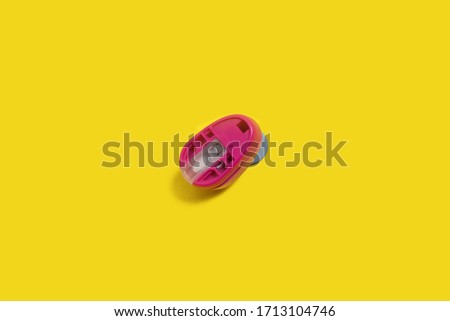 plastic pink hole puncher standing on the yellow background. concept of office chancery. free space for text
