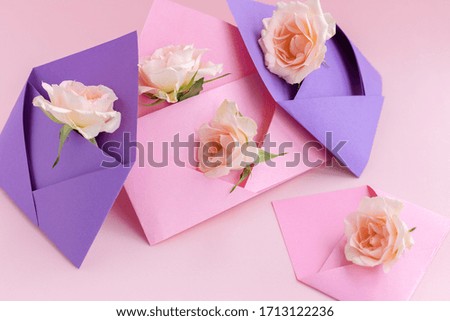 Purple and pink paper open envelopes with full small rose flowers on color background. Spring, summer concept. Romance, love notes, greeting card for March 8 International Woman's, Valentine's day.