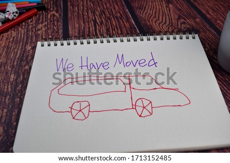 We Have Moved write on a book and drawing car Isolated on wooden table background