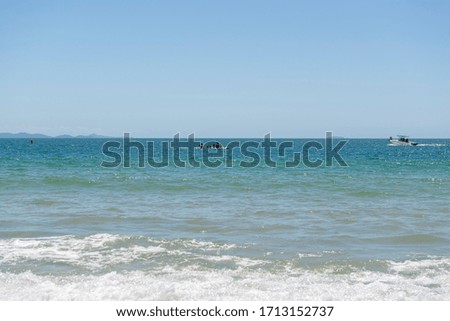 View of beautiful beach in Florianópolis, Brazil. Two men kayaking in the turquoise sea under beautiful clear sky on vacation day in tropical summer. Concept of outdoor activity in contact with nature