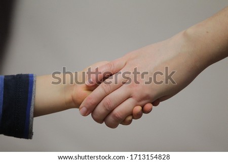 Image of a boy holding hands with his mother