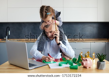 Father Working from home on laptop during quarantine. Little child girl make noise and distracts father from work on the kitchen office Royalty-Free Stock Photo #1713172234