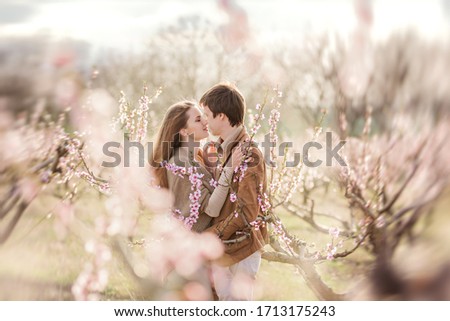 Romantic date of beautiful couple. A date near the blooming gardens. A young couple kisses on the park.