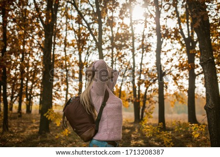 Tourist Woman Traveling In Nature, Young Caucasian Woman With Backpack Arched Her Back With Hands Behind Head And Set Face To The Sun While Standing Against Backdrop Of Autumn Trees On Sunny Day