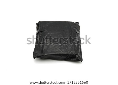 Anonymous mysterious black packet or parcel with no labels, likely from china, with unknown goods merchandising inside isolated on white. Typical low cost chinese small parcel with long delivery times