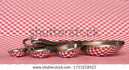 measuring spoons with reflection of red and white checkered pattern