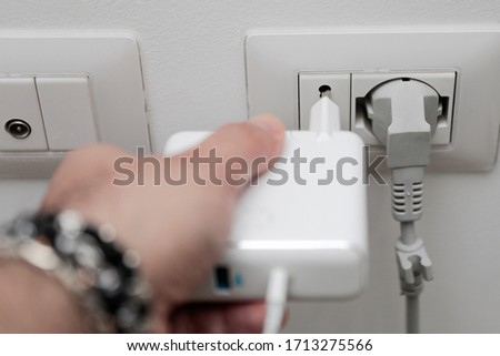 a man is about to hook a cell phone charger to the power outlet