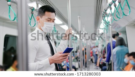 Asian business man with surgical mask face protection use a smartphone  and keep social distancing to crowd while commuting in the metro or train Royalty-Free Stock Photo #1713280303