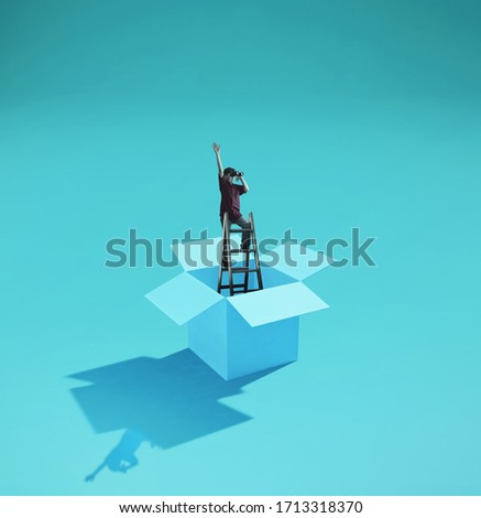 Man on a ladder looking through binoculars . Think outside the box concept . 