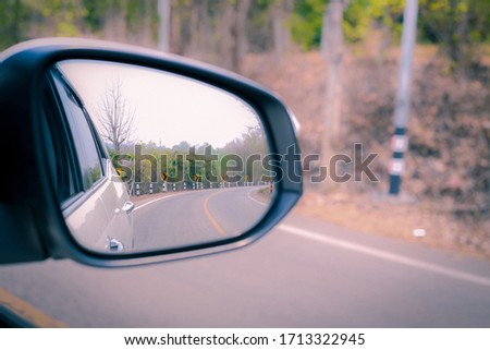 View of the road from the white car mirror.