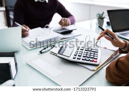 Close-up Of Two Businesspeople Calculating Financial Statement At Desk Royalty-Free Stock Photo #1713323791