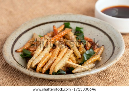 Food Insects: Bamboo worm or Bamboo Caterpillar insect deep-fried crispy for eating as food items in plate on sackcloth, it is good source of protein edible for future food. Entomophagy concept.