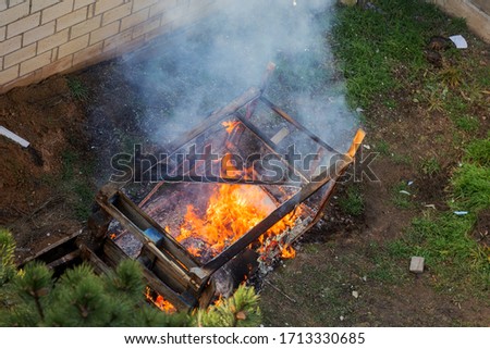 Fire coils over a burnt building. A pile of coals at the site of a burnt shed. Bright flames, flying ashes of a burning wooden building during a fire