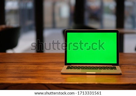 one green screen laptop computer on wooden table in cafe. 