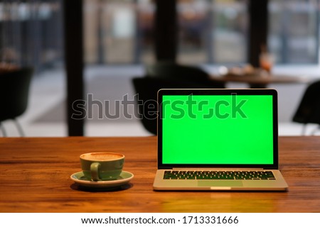 one green screen laptop computer on wooden table in cafe. blur background