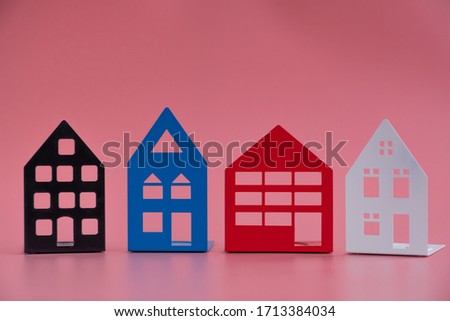 Small models of houses on a pink background