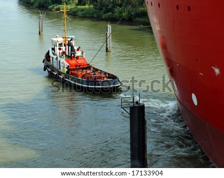 Tugboat pulling a big ocean vessel over the river out to sea