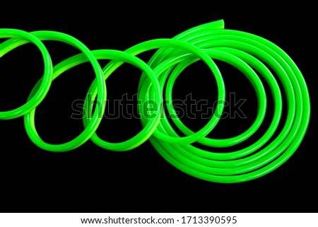Green flexible LED neon on black isolated background. Flat lay, copy space, top view. Trendy neon colors background.
