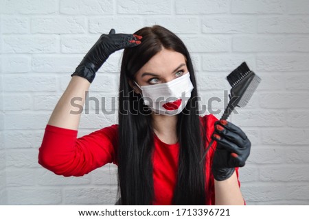Home beauty industry because of the coronavirus pandemic. A young beautiful girl in a protective mask and gloves stays at home and is engaged in beauty procedures. Girl with red lips dyes hair roots