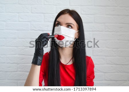 Home beauty industry because of the coronavirus pandemic. A young beautiful girl in a protective mask and gloves stays at home and is engaged in beauty procedures. Red lips and red nails