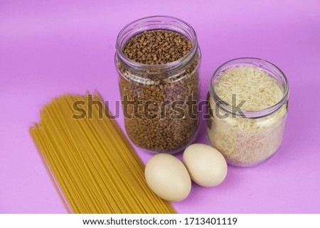 Food stock for quarantine isolation period on purple background. Rice, egg, buckwheat, spaghetti. Food delivery, Donation. Copyspace