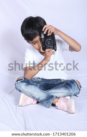 A 7 year old child is sitting on a white background clicking a photo