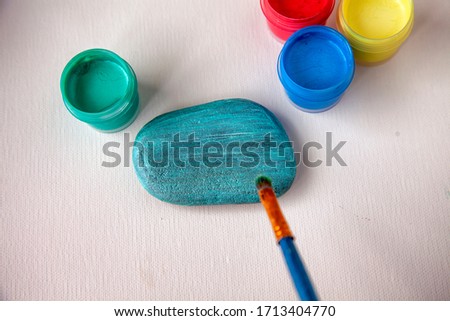 mix blue and green and draw the background on the stone with a brush.Blue cat on the stone.Work with children and adults in quarantine.manual step by step.Step 2