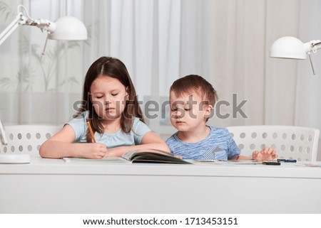 Two small children do their homework at home. The concept of home education. Distance learning