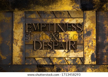 Photo of real authentic typeset letters forming Emptiness And Despair text on vintage textured grunge copper and gold background