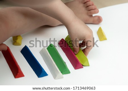 the child chooses a piece of plasticine from multi-colored blocks. hands closeup. children's creativity.
