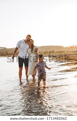 stylish man and his wife and their little son relaxing by the sea at sunset. Photo from a real family home album, their memories of a vacation on the sea