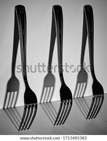 Black-and-white photo of Metal forks on a light background. Shadows from the forks. Forks stand uprigh