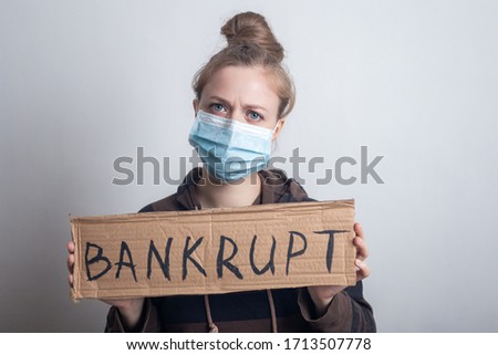 Young caucasian woman girl in mask holding banner bankrupt during coronavirus outbreak