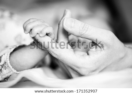 Newborn baby holding mother's hand, image with shallow depth of field 