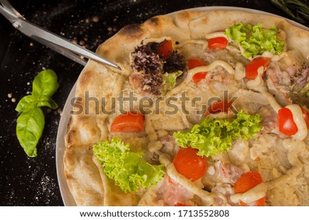 Cutting pizza with pizza scissors. On a black table - top view.