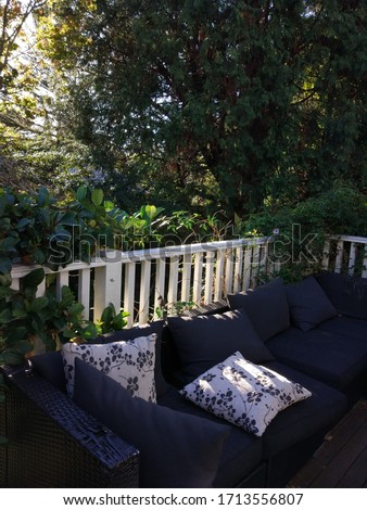 The outdoor couch and the house fence with the trees and grass int he backyard in the Blue Mountains