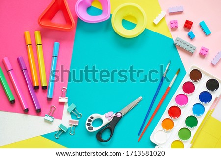 School supplies, stationery on blue background - space for caption. Child ready to draw with pencils and make application of colored paper. Top view. Royalty-Free Stock Photo #1713581020