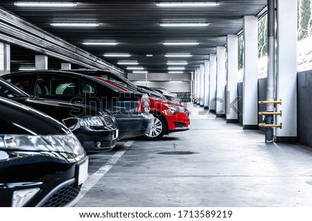 Red car paked in underground garage with lots of vehicles