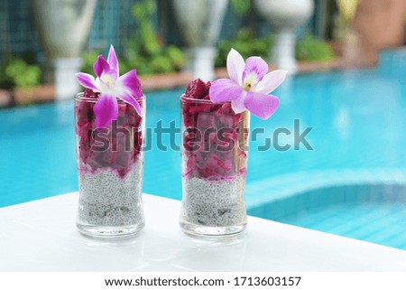 Two glasses with chia seed pudding and fruit dragon near the pool. Chia pudding  on the background of the pool. Thai fruits.