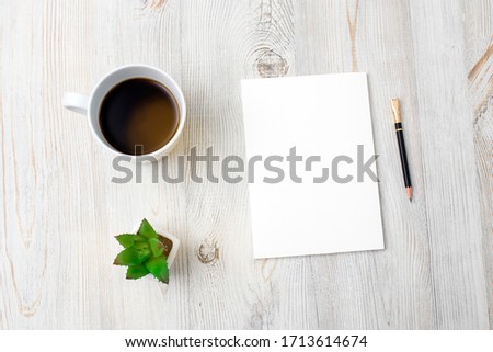 Home office workplace with cup of coffee, note pad and pen. Working from home concept. Artificial succulents in ceramic pots on a beige wooden table surface. Top view - Image. Copy space